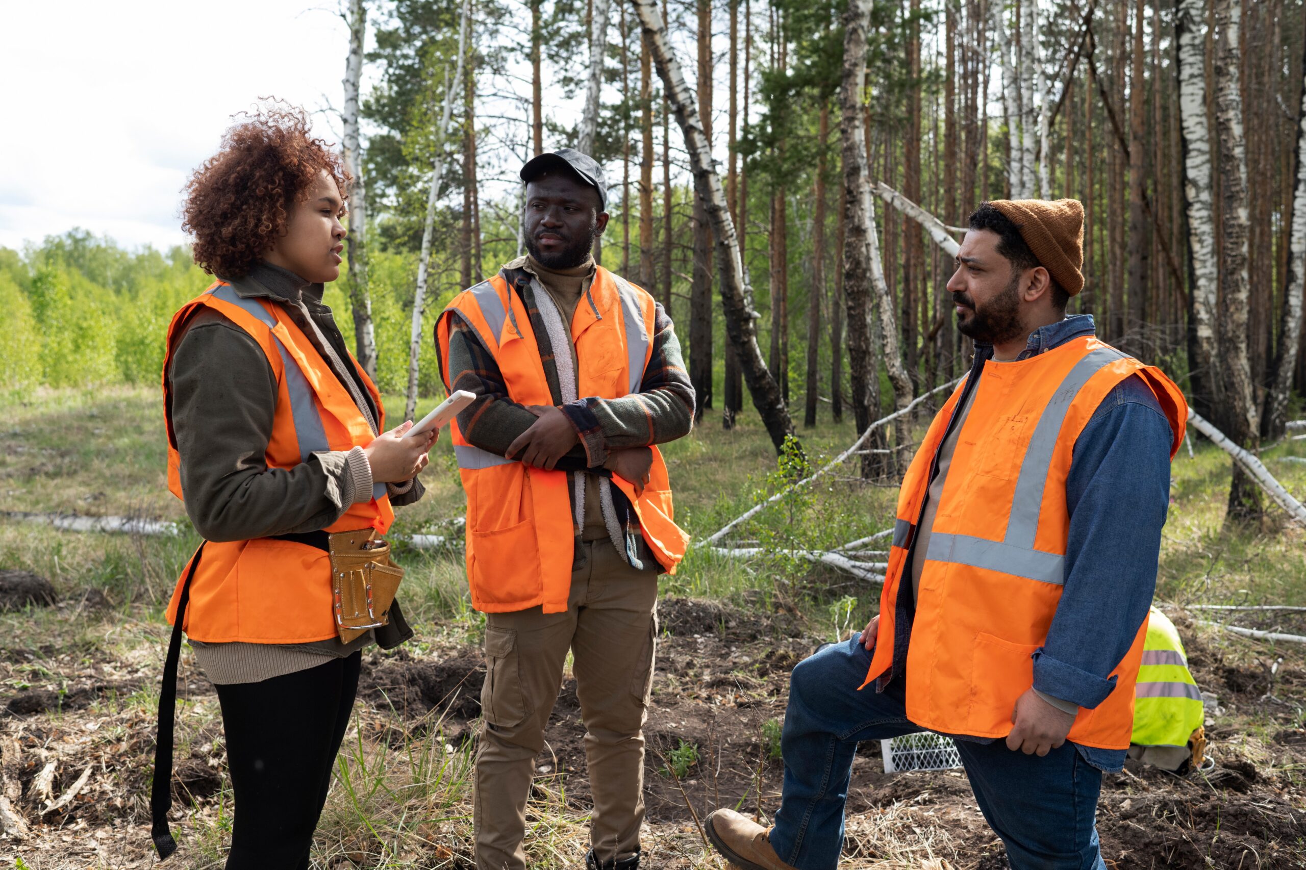 Forestry Development Authority workers in safety vests discussing sustainable forest management and policy development in the U.S. forestry industry.